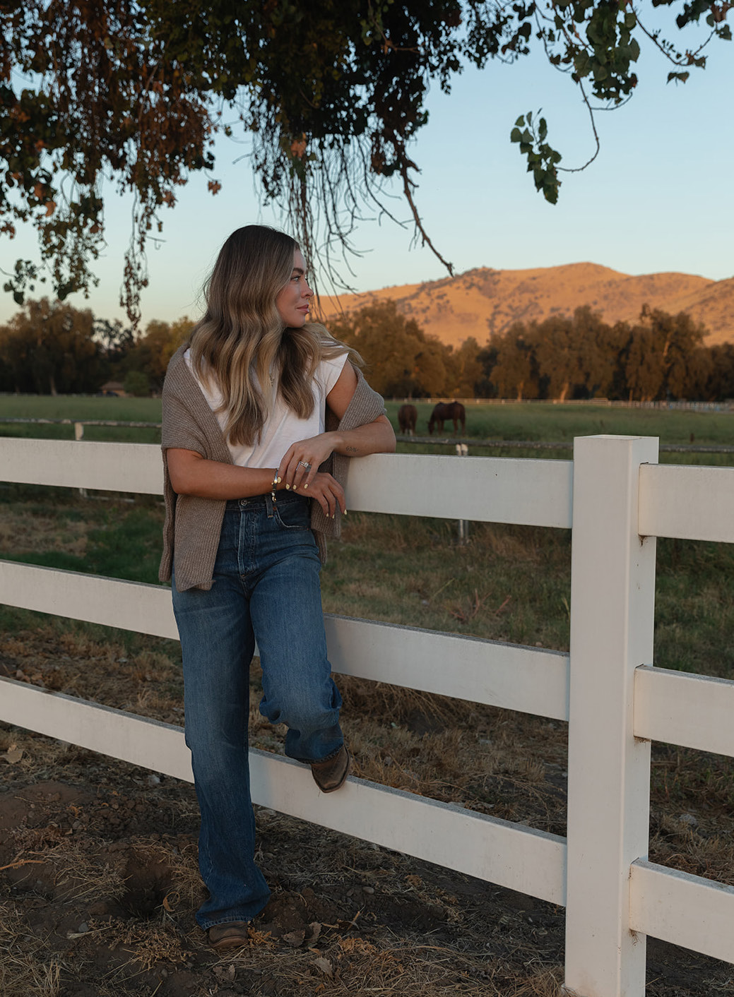 BryAnn Buhl leaning on a white ranch fence at golden hour